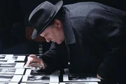 Maigret (G&eacute;rard Depardieu) sucht auf den Fotos einer Verlobungsfeier nach dem Opfer.
