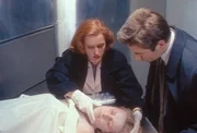 Scully (Gillian Anderson, l.) will Mulder (David Duchovny, r.) eine Phosphoressenz um Mund und Nase einer ermordeten Prostituierten zeigen, die sie bei ihrer ersten Untersuchung entdeckt hat. Scully (Gillian Anderson, l.) will Mulder (David Duchovny, r.) eine Phosphoressenz um Mund und Nase einer ermordeten Prostituierten zeigen, die sie bei ihrer ersten Untersuchung entdeckt hat.