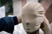 Martin Margiela legt eine Maske an einem Modell an. Der 1957 geborene belgische Modedesigner inspiriert bis heute viele seiner j&uuml;ngeren Kolleginnen und Kollegen, ohne sein Gesicht in der &Ouml;ffentlichkeit gezeigt zu haben.