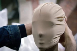 Martin Margiela legt eine Maske an einem Modell an. Der 1957 geborene belgische Modedesigner inspiriert bis heute viele seiner j&uuml;ngeren Kolleginnen und Kollegen, ohne sein Gesicht in der &Ouml;ffentlichkeit gezeigt zu haben.