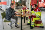 Jan Maybach (Marco Girnth, l.) spricht bei einer gemeinsamen Pizza mit seinem Sohn Benni Maybach (Maximilian Klas, M.) und dessen Kollegen Lukas Schaaf (Philip Birnstiel, r.) über die Herausforderungen, die die Rettungssanitäter täglich zu bewältigen haben. Jan Maybach (Marco Girnth, l.) spricht bei einer gemeinsamen Pizza mit seinem Sohn Benni Maybach (Maximilian Klas, M.) und dessen Kollegen Lukas Schaaf (Philip Birnstiel, r.) über die Herausforderungen, die die Rettungssanitäter täglich zu bewältigen haben.
