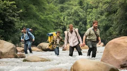 Die Backpacker Kevin (Alex Russell, l.), Yossi (Daniel Radcliffe, M.), Marcus (Joel Jackson, 2.v.r.) durchqueren mit ihrem Expeditionsf&uuml;hrer Karl (Thomas Kretschmann, r.) einen Fluss im Dschungel.