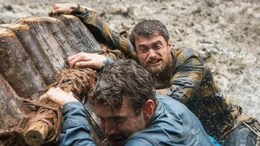 Das Flo&szlig; von Yossi (Daniel Radcliffe, r.) und Kevin (Alex Russell, l.) l&auml;uft bei starker Str&ouml;mung auf einem Felsen auf.
