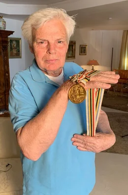 25 Jahre nach den Atombombenabw&uuml;rfen in Japan finden 1964 die Olympischen Sommerspiele in Tokio statt. Mitten im Kalten Krieg sollen die Spiele zu einem Symbol f&uuml;r eine friedliche Welt werden. Insbesondere das geteilte Deutschland soll dies unter Beweis stellen: Auf Anordnung des IOC m&uuml;ssen beide deutsche Staaten trotz tiefer ideologischer Gr&auml;ben mit einer gemeinsamen Mannschaft in Tokio antreten. - Lothar Claesges in seinem Haus 2019.