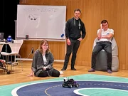 Studentin Alina Harant und Senior Research Assistants beobachten den Lernerfolg des Deep Racer auf der Rennbahn.