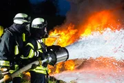 Feuerwehrmann - Feuerwehrleute beim Löschen eines Großbrandes, sie stehen mit Schutzkleidung vor einer Feuerwand. Feuerwehrmann - Feuerwehrleute beim Löschen eines Großbrandes, sie stehen mit Schutzkleidung vor einer Feuerwand.