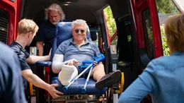 Volker (Henry H&uuml;bchen, M.) wird vom Krankenwagen "geliefert". Er hat einen Arm und einen Bein in Gips. Sanit&auml;ter (Jasper Diedrichsen, l., Frank Smolarek, 2.v.l.) heben ihn aus dem Wagen.
