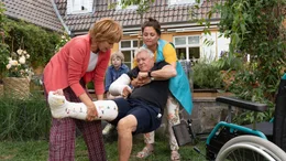 Doro (Ulrike Kriener, l.) und ihre Putzfrau Suzy (Inga Quotadamo, r.) hieven Volker (Henry H&uuml;bchen, 2.v.r.) gemeinsam zur&uuml;ck in den Rollstuhl. Enkel Jakob (Zacharias Zeh, M.) schaut zu.