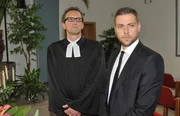 Der Pastor (Thomas Hollaender, li.) und John Bachmann (Felix v. Jascheroff) wissen nicht, was Pia mit der Unterbrechung der Trauerfeier von Verena bezweckt.