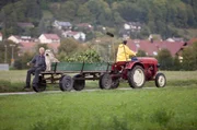Urban Fuchs (Peter Bongartz) und sein Hund Herr Kaiser nutzen eine Mitfahrgelegenheit auf dem Traktor-Anh&auml;nger.