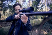 Andreas (Tom Schilling) hat ein Gewehr im Wald gefunden und richtet es auf seine Team-Mitglieder.
