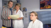 Tim (Oliver Reinhard) bringt den neuen OP-Plan und Borstel (Kerstin Thielemann, re.) soll nun doch operieren. Aber f&uuml;r Nikola (Mariele Millowitsch) sieht es nicht so aus, als w&uuml;rde Borstel sich wahnsinnig freuen.