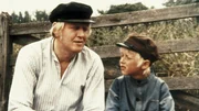Alfred (Bj&ouml;rn Gustafsson) und Michel (Jan Ohlsson) sitzen auf der Bank und beobachten, wie Lina mit einem fremden Bauern flirtet.
