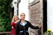 Kristin (Nina Schmieder, l.) zwingt Theresa (Ines Lutz, r.) mit vorgehaltener Waffe, zu Doris ins dunkle Versteck.