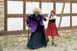 Rotk&auml;ppchen (Kathleen Frontzek) wird von einer alten, hinkenden Frau (Heta Mantscheff) zu einer verwitterten H&uuml;tte im Dorf gezogen.