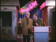 Quizmaster Drew (John Griffin, r.) stellt Mark (Dick Van Dyke, M.) als neuen Kandidaten der Sendung vor. Quizmaster Drew (John Griffin, r.) stellt Mark (Dick Van Dyke, M.) als neuen Kandidaten der Sendung vor.
