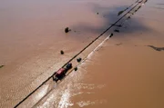 Ein Fahrzeug kriecht auf einer &uuml;berfluteten Stra&szlig;e in Thessalien, Griechenland, voran, w&auml;hrend das Hochwasser des Zyklons ''Daniel'' die umliegende Landschaft in alle Richtungen verschlingt.