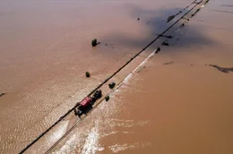 Ein Fahrzeug kriecht auf einer &uuml;berfluteten Stra&szlig;e in Thessalien, Griechenland, voran, w&auml;hrend das Hochwasser des Zyklons ''Daniel'' die umliegende Landschaft in alle Richtungen verschlingt.