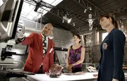 Professor Bunsen Jude (David Alan Grier) liefert Brennan (Emily Deschanel, r.) und Cam (Tamara Taylor) sachdienliche Hinweise f&uuml;r ihren Fall. F&uuml;r seine Hilfe soll Brennan in seiner Kinderwissenschaftsshow auftreten.