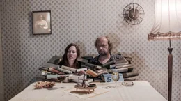 Mutter (Beate D&uuml;ber) und Vater (Matthias Zwarg ) sitzen vor einem Berg B&uuml;cher.