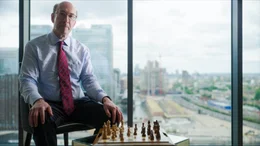 Der &Ouml;konom Kenneth Rogoff sitzt vor einem Schachbrett. Im Hintergrund sieht man das Londoner Bankenviertel.