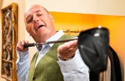 Hubert (Bernhard Ulrich) freut sich &uuml;ber den neuen, teuren Golfschl&auml;ger, den er sich gekauft hat.