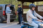 Von links: Komparse, Polizist Haas (Michael Dietmayr) und Hacki (Timo Baran). Polizist Haas ist fassungslos, als Hacki auf seinem Moped mit hoher Geschwindigkeit an ihm vorbeirast.
