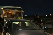 Baqir (Vassilis Koukalani) sitzt im Auto, ger&auml;t in eine Kontrolle der Taliban - und f&uuml;rchtet um das Leben seiner Frau Zahara. Erwan (Thibaut Evrard, r.) versucht, die Lage unter Kontrolle zu halten, w&auml;hrend im Hintergrund afghanische Mitarbeiter der Franzosen im Bus ausharren.
