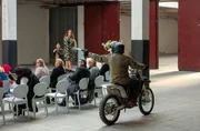 Der Attentäter schießt vom Motorrad aus auf eines der Models auf dem Laufsteg. Der Attentäter schießt vom Motorrad aus auf eines der Models auf dem Laufsteg.