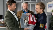 Die Kommissare Hansen (Igor Jefti?, l.) und Stadler (Dieter Fischer, M.) erhoffen sich aufschlussreiche Informationen aus den Unterlagen, die Polizeihauptmeister Mohr (Max M&uuml;ller, r.) aus dem Haus des Opfers mitbringt.