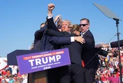 Der ehemalige US-Pr&auml;sident Donald Trump erhebt den Arm, w&auml;hrend Blut &uuml;ber sein Gesicht l&auml;uft, bei einer Wahlkampfveranstaltung auf dem Gel&auml;nde der Butler Farm Show in Butler, Pennsylvania. Trump duckte sich und wurde von der B&uuml;hne gebracht, nachdem laute Ger&auml;usche zu h&ouml;ren gewesen waren.