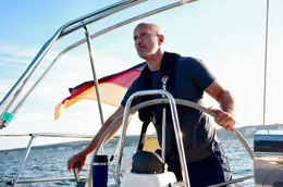 Schauspieler und Ostseeliebhaber Benno F&uuml;rmann am Steuer eines Segelschiffes auf der Ostsee w&auml;hrend der Dreharbeiten zum Film &bdquo;Ostsee am Limit&ldquo;.