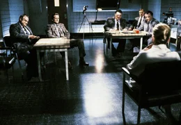 Catherine Tramell (Sharon Stone, rechts) wird von einigen Polizisten verh&ouml;rt, darunter Detective Nick Curran (Michael Douglas, 2. von links) und sein cholerischer Kollege Gus (George Dzundza, links).