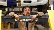In the workshop, Richard Hammond looks at camera inquisitively with tools in hand. Landscape, midshot.