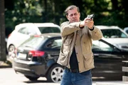 Finn (Sven Martinek) sichert sich und seinen Kollegen, mit gezogener Waffe.