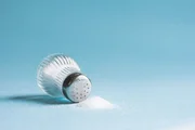 Spilled salt and saltshaker on blue background Spilled salt and saltshaker on blue background