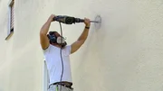 Mike Schopp bohrt die Au&szlig;enwand f&uuml;r die Abzugshaube der K&uuml;che an.