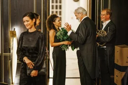 Der erfolgreiche Dirigent Walter Kler (Peter Simonischek, 2.v.r.) feiert seinen j&uuml;ngsten Erfolg mit den Mitgliedern seines Orchesters (Komparsen, r. und 2.v.l.) und Irene von Glaubitz, der Frau des Intendanten (Katrin Anne He&szlig;, l.). Besonders die talentierte Pianistin Natalie Noirot (Petra Michelle N&eacute;rette, M.) hat Walter beeindruckt.
