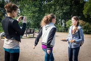 Annalena (Zarina Z&ouml;ller, l.) filmt ihre Freundin Britta (Vivien Fr&ouml;hlich, M.), als sie Svenja (Carol Garnier, r.) Schl&auml;ge androht.