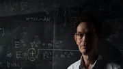 Astrophysiker Neil Turok vor einer Tafel mit physikalischen Formeln. Astrophysiker Neil Turok vor einer Tafel mit physikalischen Formeln.