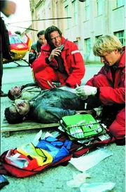 Dr. Michael L&uuml;dwitz (Rainer Grenkowitz, M.) und der Sanit&auml;ter Peter Berger (Serge Falck, r.) k&uuml;mmern sich um verletzte Arbeiter (Komparsen), die Opfer einer Bombenexplosion wurden.