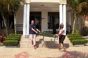 Marco und Dianne tragen ein Trampolin vors Haus