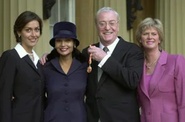 Michael Caine (2.v.r.) mit seinen zwei T&ouml;chtern (au&szlig;en) und Ehefrau Shakira (2.v.l.) bei der Verleihung der Ritterw&uuml;rde durch die Queen im Jahr 2000