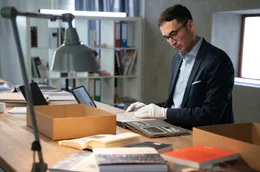Dr. Stefan H&ouml;rdler mit Album an Schreibtisch