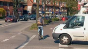 Ein Fahrradfahrer fährt knapp vor einem Transporter über die Straße. Ein Fahrradfahrer fährt knapp vor einem Transporter über die Straße.