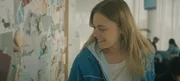 Charlie (Roos Dickmann) amüsiert sich im Wartebereich der Kinderwunschklinik über die ungewöhnlichen Namen einiger Kinder, die auf Geburtskarten zu lesen sind. Charlie (Roos Dickmann) amüsiert sich im Wartebereich der Kinderwunschklinik über die ungewöhnlichen Namen einiger Kinder, die auf Geburtskarten zu lesen sind.