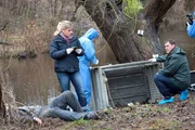 Am Ufer der Trave wird der Inhaber einer Sch&ouml;nheitsklinik tot aufgefunden (Komparse, liegend). Das Ermittlerduo Finn Kiesewetter (Sven Martinek, r.) und Sandra Schwartenbeck (Marie-Luise Schramm, l.)  vermutet, dass das Opfer gefoltert wurde.