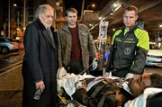 Hauptmann Furrer (Pierre Kiwitt, Mitte.) und Borchert (Christian Kohlund, li.) versuchen mit dem schwer verletzten Investigativ-Journalisten Nuka Baluba (Pierre Rousselet) zu sprechen. Hauptmann Furrer (Pierre Kiwitt, Mitte.) und Borchert (Christian Kohlund, li.) versuchen mit dem schwer verletzten Investigativ-Journalisten Nuka Baluba (Pierre Rousselet) zu sprechen.
