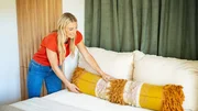 Host Jasmine Roth adds the final touches onto the Smith bedroom by fluffing pillows and tidying up. Host Jasmine Roth adds the final touches onto the Smith bedroom by fluffing pillows and tidying up.