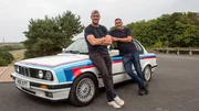 Ant Anstead, wearing black tshirt and jeans, and Duncan Cowper, leaning against the side of the BMW, after renovation, shot taken at millbrook proving ground, trees and roads in background Ant Anstead, wearing black tshirt and jeans, and Duncan Cowper, leaning against the side of the BMW, after renovation, shot taken at millbrook proving ground, trees and roads in background